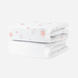 Two folded Newton Baby Breathable, Organic Cotton Sheets (2-pack), featuring a pink star pattern, are stacked together against a plain white background.