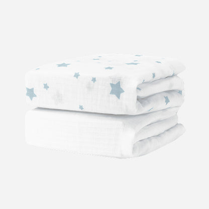 Two Breathable, Organic Cotton Sheets (2-pack) by Newton Baby, featuring a light blue star pattern, are neatly folded and stacked together on a plain white background.