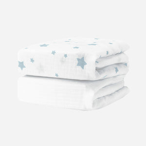 Two Breathable, Organic Cotton Sheets (2-pack) by Newton Baby, featuring a light blue star pattern, are neatly folded and stacked together on a plain white background.