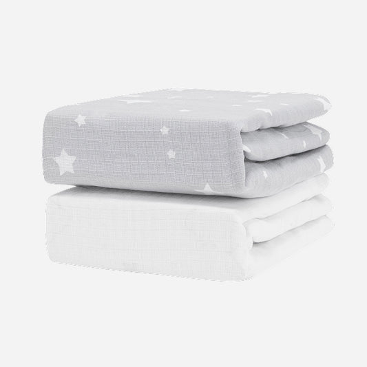 The Newton Baby Breathable, Organic Cotton Sheets (2-pack) includes one light gray sheet with white stars and one plain white sheet, both folded and set against a white background.