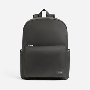 The Newton Lorimer Diaper Bag by STATE for Newton Baby is a simple black backpack with a front zip pocket, small side pockets, top handle, and a rectangular label on the front. Stylish and practical diaper bag. Background is plain white.
