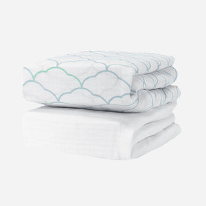 Newton Baby Breathable, Organic Cotton Sheets (2-pack): one features a light blue and green scallop design, the other is plain white. Both hypoallergenic crib sheets are shown folded on a white background for a crisp, clean look. 