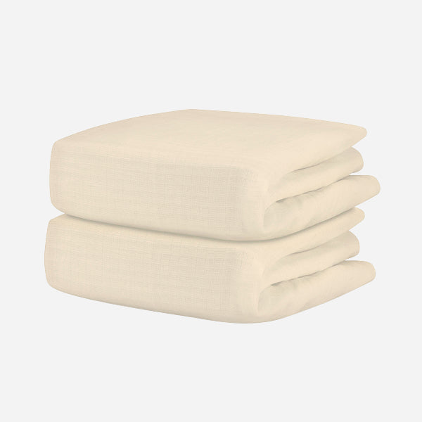 A neatly folded, cream-colored textured blanket pairs beautifully with Newton Baby’s Breathable Organic Cotton Sheets (2-pack), creating a cozy, comfortable nursery.