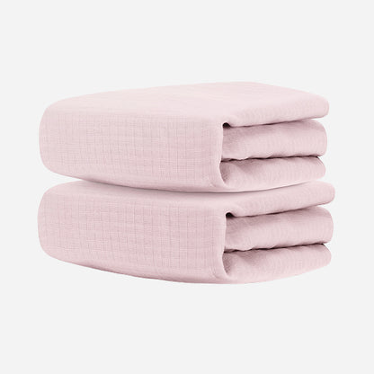Two folded Newton Baby Breathable, Organic Cotton Sheets (2-pack), light pink in color, stacked against a plain white background.