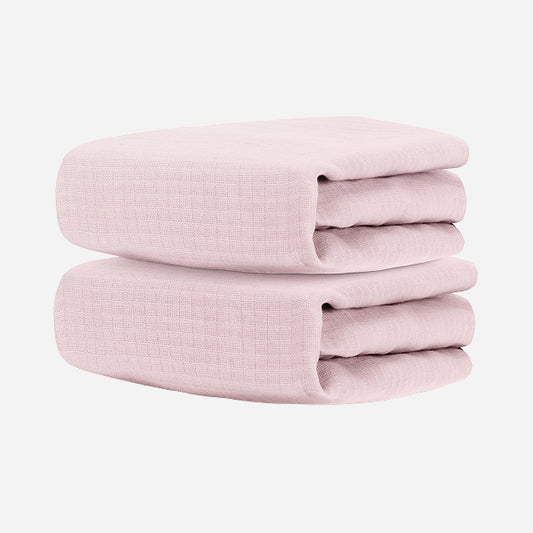 Two folded Newton Baby Breathable, Organic Cotton Sheets (2-pack), light pink in color, stacked against a plain white background.