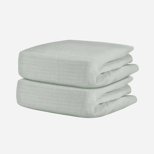 A neatly folded, light gray Breathable, Organic Cotton Sheet from Newton Baby (2-pack) with a subtle textured pattern is displayed against a plain white background.