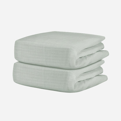 A neatly folded, light gray Breathable, Organic Cotton Sheet from Newton Baby (2-pack) with a subtle textured pattern is displayed against a plain white background.