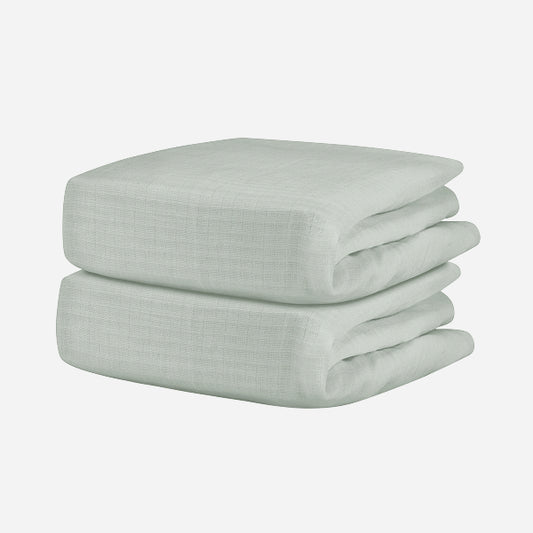 A neatly folded, light gray Breathable, Organic Cotton Sheet from Newton Baby (2-pack) with a subtle textured pattern is displayed against a plain white background.