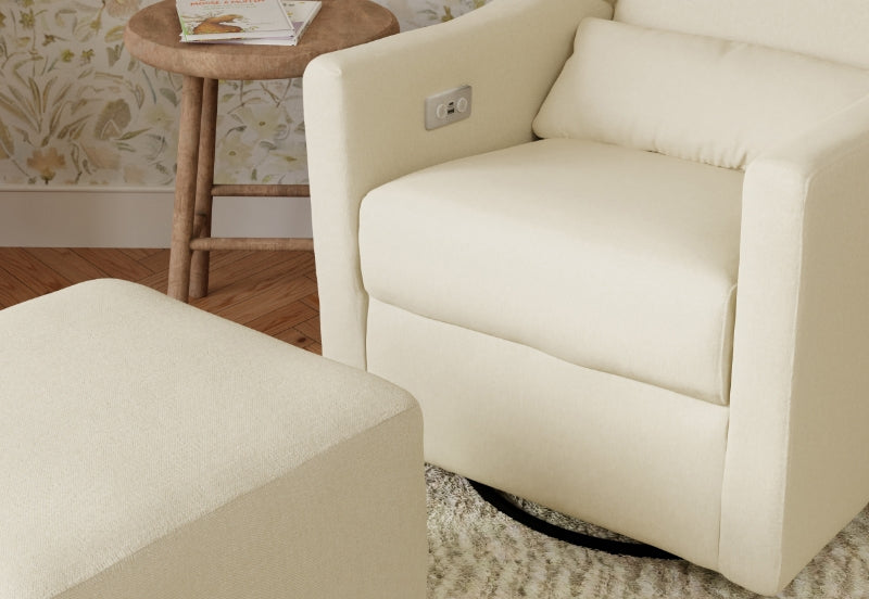 Cream-colored nursery armchair with matching ottoman in a serene room setting.