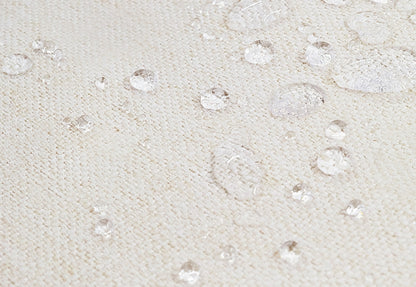 Close-up image of a waterproof beige fabric with scattered clear water droplets demonstrating water resistance.