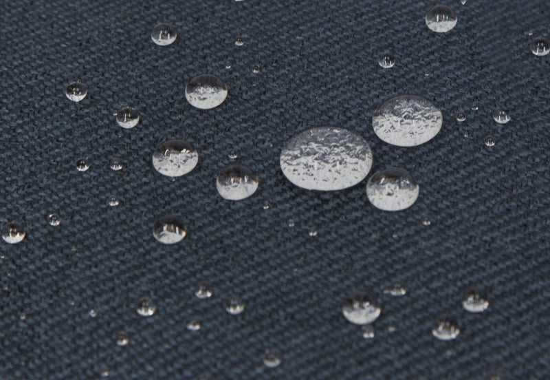 Close-up view of water droplets on a textured dark blue fabric surface.