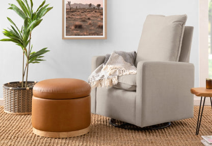 Cozy nursery corner featuring a modern gray glider chair with a matching ottoman, light throw blanket, and a lush green plant, next to a framed savannah landscape photo.