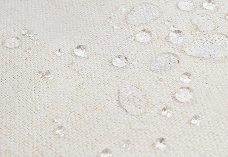 Close-up of a waterproof fabric with droplets of water demonstrating its water-resistant texture.