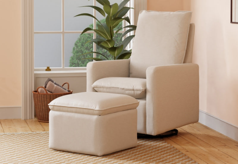 A cozy nursery corner featuring a cream-colored glider chair with a matching ottoman, set beside a green plant and a basket of blankets.
