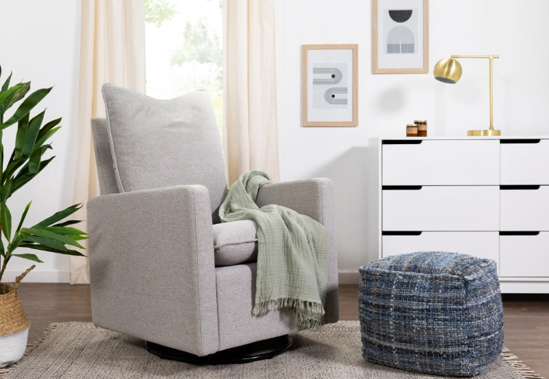 A cozy, modern living room featuring a gray upholstered swivel chair with a green throw blanket, accompanied by a blue ottoman and elegant decor.