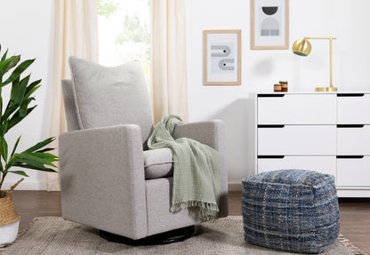 A cozy, modern living room featuring a gray upholstered swivel chair with a green throw blanket, accompanied by a blue ottoman and elegant decor.