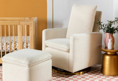 A cozy nursery featuring a cream chair with a matching ottoman, beside a wooden crib and a small gold side table with a plant.