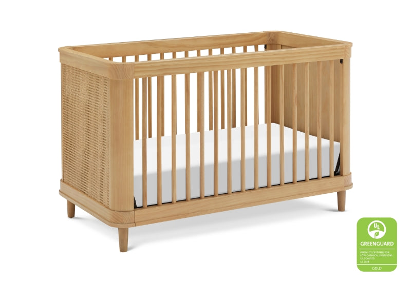 Modern wooden crib with a white mattress, featuring vertical slats and a Greenguard certification seal.