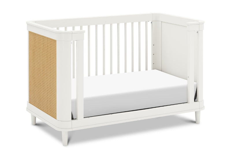 White baby crib with a modern design featuring a slatted front and a side panel with a woven texture.