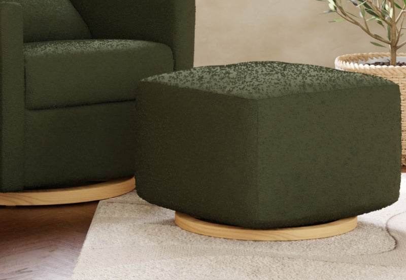 Dark green fabric nursery ottoman with light wooden base, coordinated with matching armchair in a home setting.