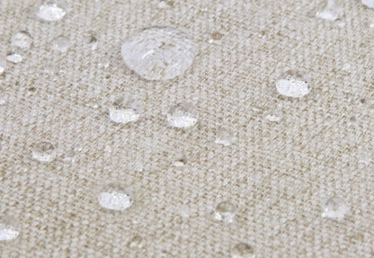 Close-up image of water droplets on a beige textile surface, demonstrating waterproof material.