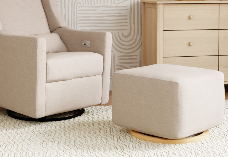 A cozy nursery room with a modern gliding chair and matching ottoman on a textured rug, next to a wooden dresser and decorated with a subtle, abstract wall design.