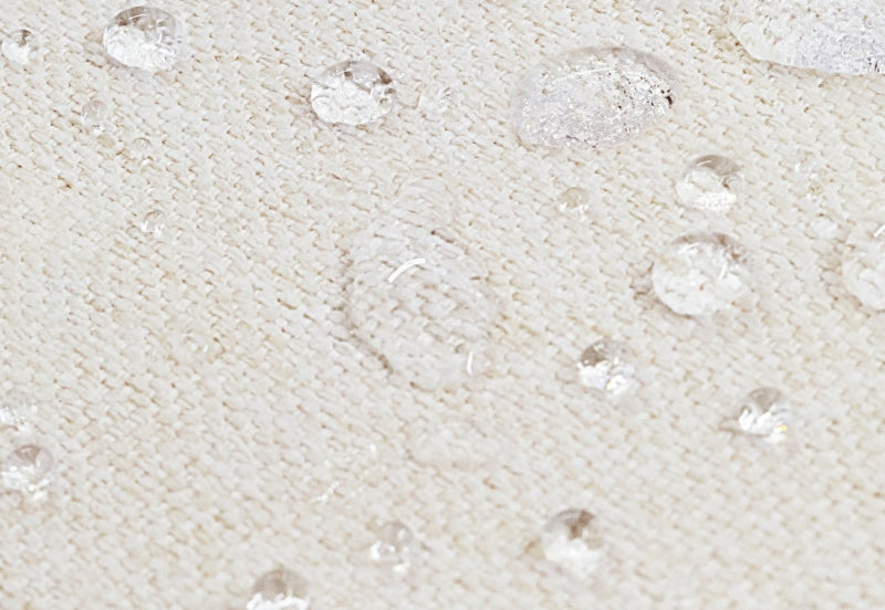 Close-up of a breathable, waterproof mattress with water droplets demonstrating its water-resistant surface.