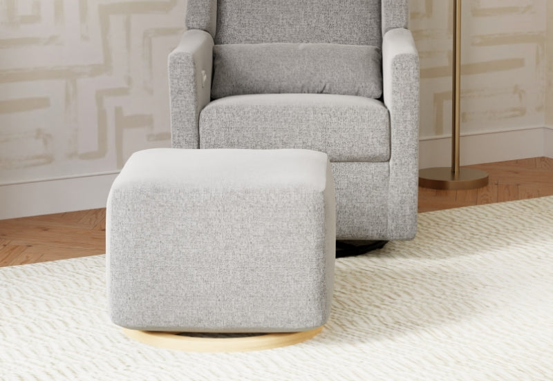 A modern grey nursing chair and ottoman set on a white textured rug in a stylish room.