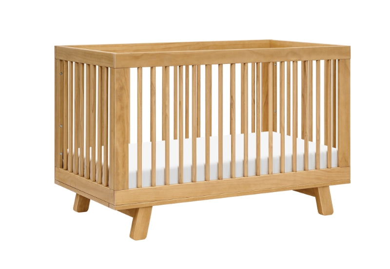 A sturdy natural wood baby crib with vertical slats and a solid base, isolated on a white background. 999-8501-HNY