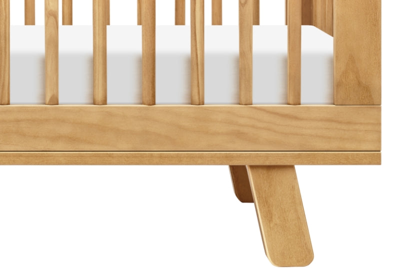 Close-up of a modern wooden baby crib showcasing its sturdy slats and sleek leg design.