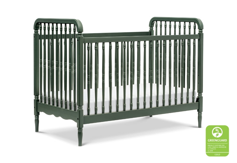 Green vintage-style crib with a white mattress, featuring a "GREENGUARD GOLD" certification logo in the bottom right corner.