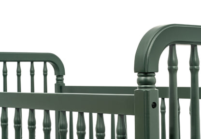 Classic green baby crib with traditional spindle design and curved headboard, isolated on a white background.