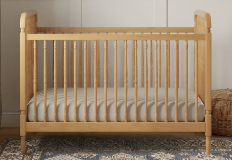Wooden baby crib with a breathable mattress in a cozy room setting.