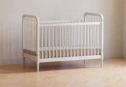 Minimalist white baby crib positioned on a wooden floor against a neutral wall, offering a simple and safe sleeping solution for infants.