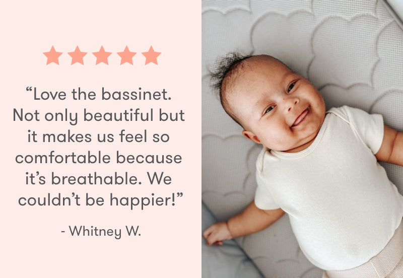 A cheerful baby in a white onesie lies on a breathable bassinet mattress, with a testimonial by Whitney W. saying: "Love the bassinet. Not only beautiful but it makes us feel so comfortable because it's breathable. We couldn't be happier!" alongside a five-star rating.