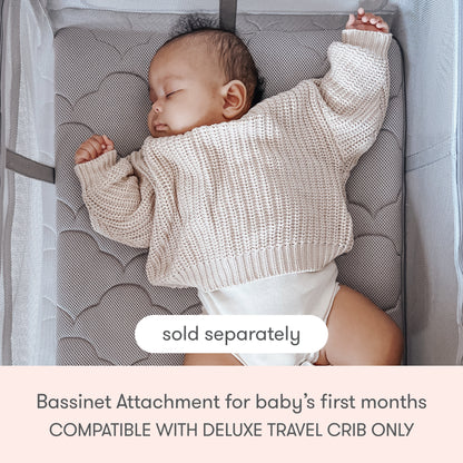 A baby sleeps on their back in a crib, wearing a cream knit sweater and white diaper. Text reads: Bassinet Attachment with breathable mattress for baby's first months, sold separately. Compatible only with Newton Baby Deluxe Travel Crib & Play Yard.