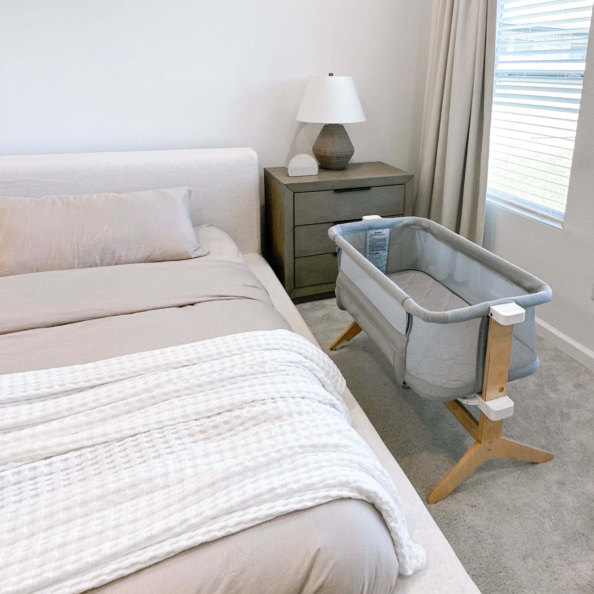 A serene nursery featuring a grey Newton baby crib in a well-organized room with neutral-toned decor.