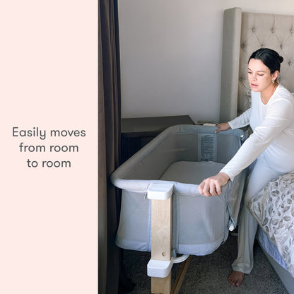 A woman smiling while demonstrating a portable baby bassinet with the caption "Easily moves from room to room."