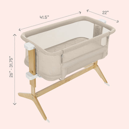 The Newton Baby Bassinet & Bedside Sleeper features breathable mesh sides, wooden legs, and a Wovenaire mattress. Adjustable height from 26"–31.75", it measures 41.5"x22". Cozy for your baby as a bedside sleeper on a light pink background.