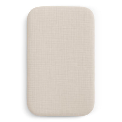 The image shows Newton Baby Bassinet Extra Sheets, rectangular and beige, designed for bedside sleepers or bassinets. The fabric has a subtle textured pattern and a smooth, clean look, displayed against a white background.