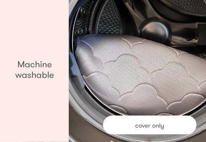 A cushioned gray bassinet cover displaying a patterned design, labeled as 'Machine washable cover only', inside a washing machine.