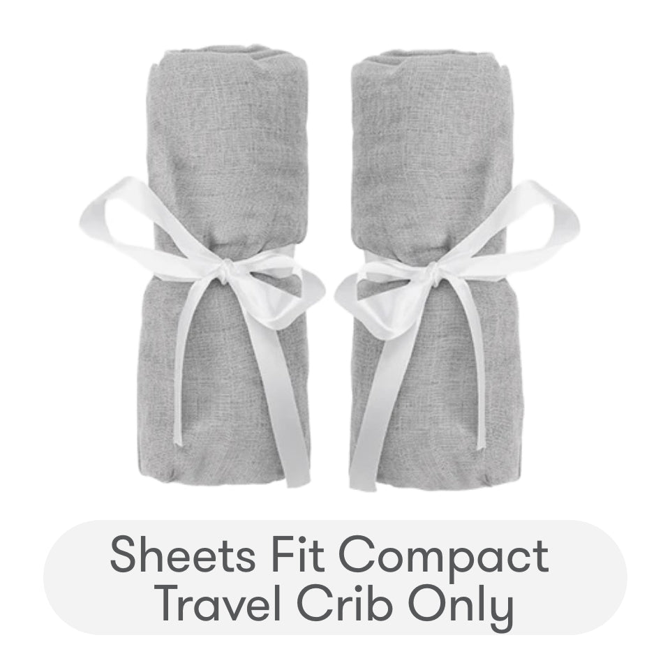 Two rolled-up gray Newton Baby Compact Travel Crib Sheets, each tied with a white ribbon, are shown side by side above text stating: Sheets fit Compact Travel Crib only—ideal for use as travel crib sheets or play yard mattress sheets.
