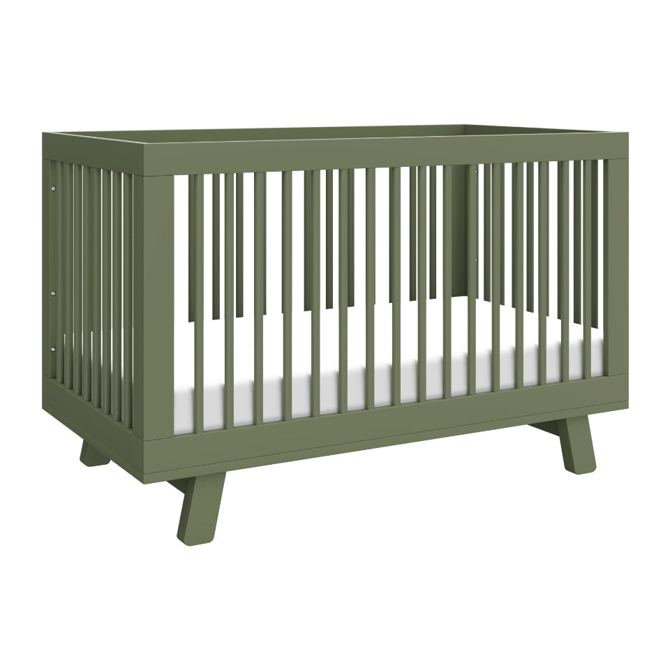 The Babyletto Hudson Convertible Crib features a modern olive green design with slatted sides, angled legs, and a white mattress—ideal for transitioning from crib to toddler bed as your child grows.
