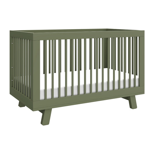 The Babyletto Hudson Convertible Crib features a modern olive green design with slatted sides, angled legs, and a white mattress—ideal for transitioning from crib to toddler bed as your child grows.