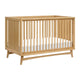 The Babyletto Peggy Convertible Crib features vertical slats, a white mattress, and angled legs. With a natural wood finish and minimalist mid-century style, it's ideal for any modern nursery. skip