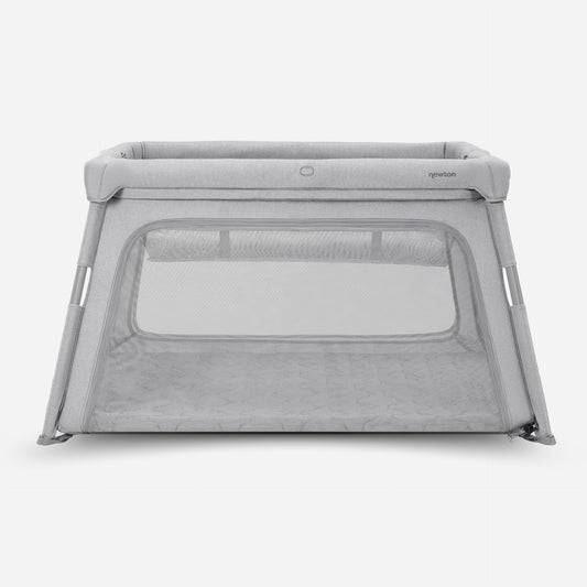 The Newton Baby Deluxe Travel Crib & Play Yard is a gray, rectangular playpen featuring mesh sides and a soft, cushioned base, pictured against a plain white background.