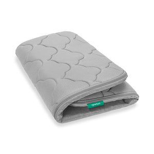 The Newton Baby Extra Bassinet Mattress Cover is gray, quilted, and textured with a small green Newton tag on the side; it’s machine washable for easy care.