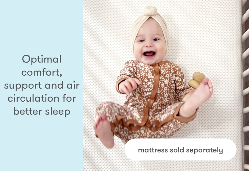 Happy baby wearing a floral outfit and headband lies on a mattress, with text emphasizing 'Optimal comfort, support and air circulation for better sleep - mattress sold separately.'