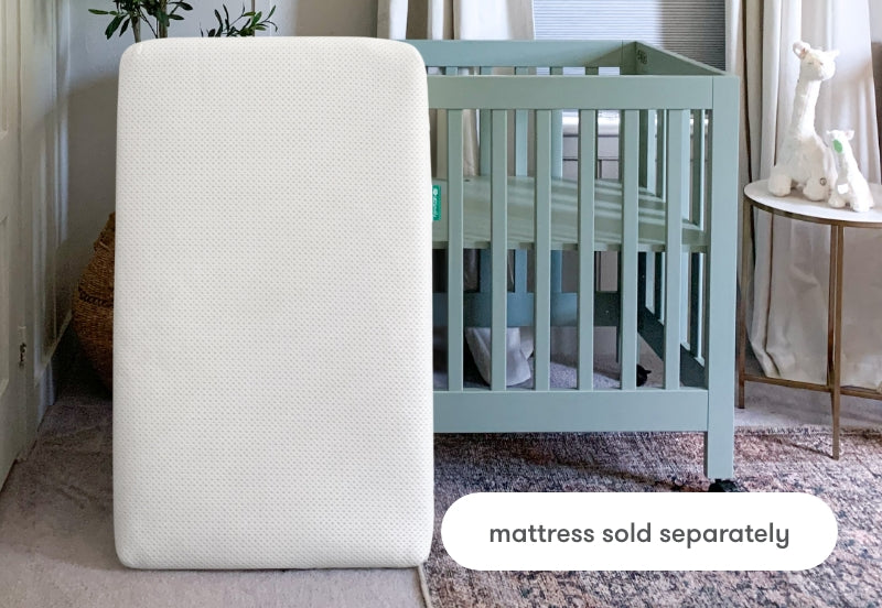 Breathable baby crib mattress prominently displayed in front of a stylish, mint green crib with the note "mattress sold separately" at the bottom.