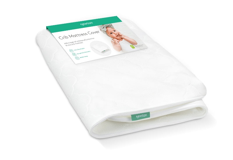 Newton Crib Mattress Crib with a product label featuring a smiling baby, emphasizing its breathable and washable design.